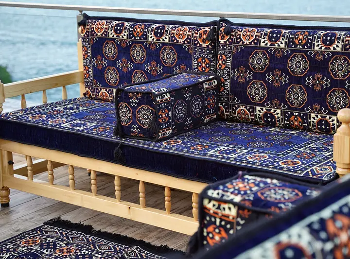 Close view of navy gul backrest pillows and a boxy armrest bolster resting on a wooden bench frame