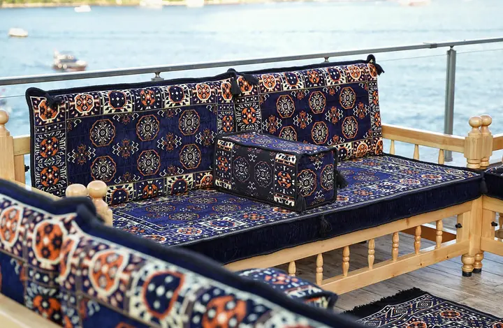 Angled close view of a wooden bench with navy blue octagonal medallion cushions and turned corner posts