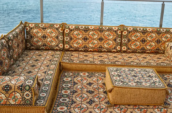 Gold Afghan Gul corner where the two seat runs meet, with a square ottoman resting on a patterned rug