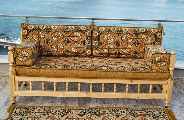 Front view of one wooden bench with a gold quartered-gul seat, two backrest pillows and armrest bolsters