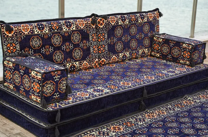 Close angled view of navy gul medallions across the backrests of a straight floor seat, box armrests resting on the seat cushion