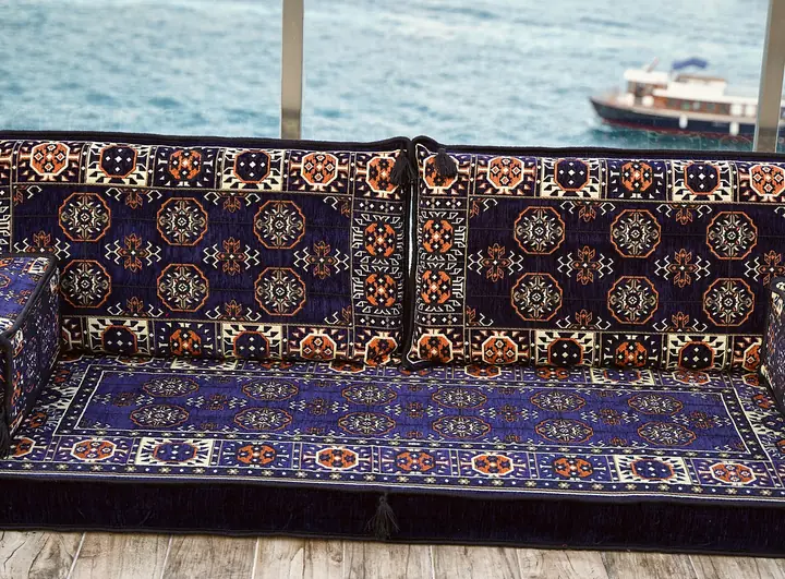 Front view of a navy blue Afghan Gul seat with two patterned backrests and the edges of box armrests at each end