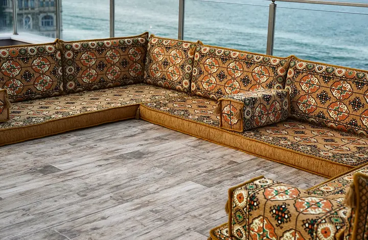 Wide angled view of gold three-sided floor seating with octagonal guls on the backrests and armrest bolsters at the ends