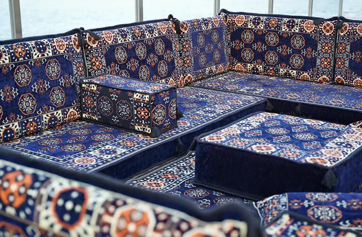 High view of a navy blue corner where two runs of gul backrests meet behind a square ottoman