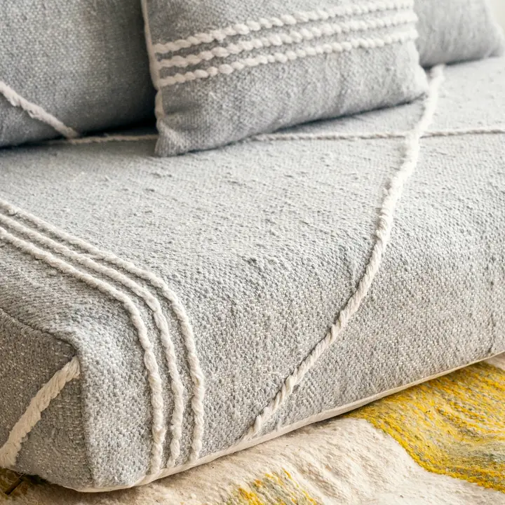 Close view of a light gray seat cushion edge, showing the flat weave and white stripes of the cotton cover