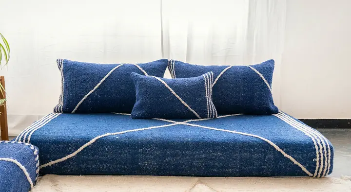 Navy blue woven floor couch with a white diamond line pattern and matching pillows on a cream rug