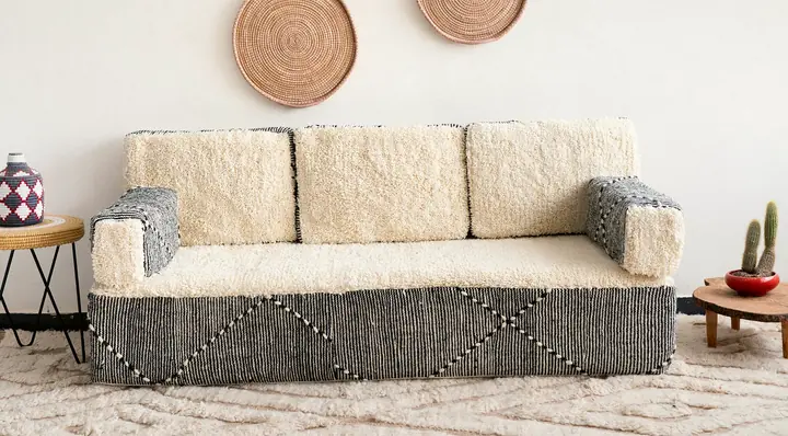 Cream shag loveseat floor couch with striped woven arms and base, set below two woven wall baskets