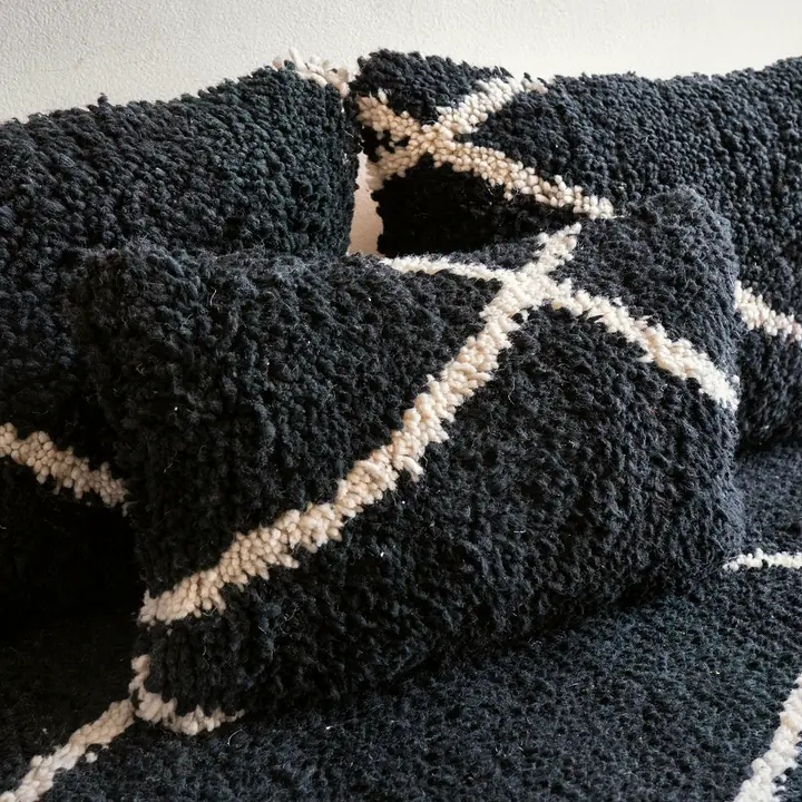 Close view of black shag back cushions with a white line pattern and a lumbar pillow resting on the seat