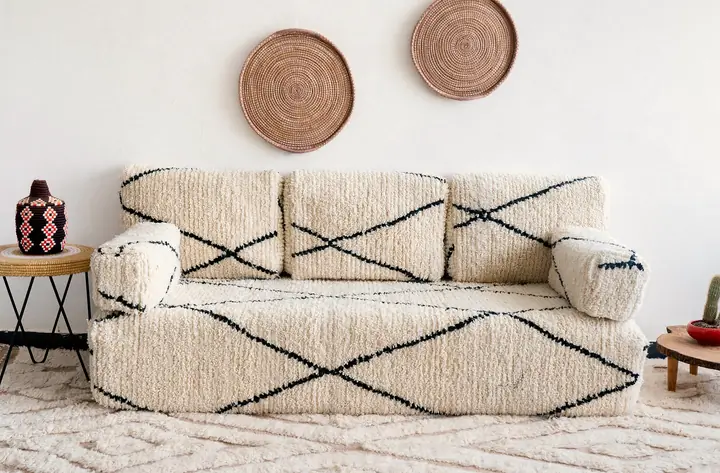 Cream shaggy floor couch with a black line pattern, set below woven wall plates between two side tables
