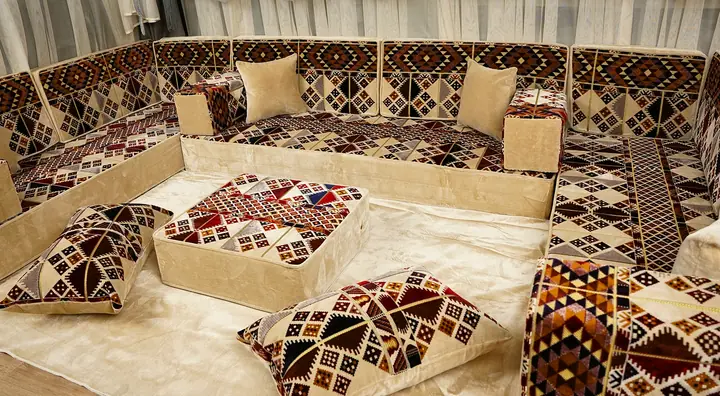Geometric patterned backs and side panels surround plain beige seats, with a matching ottoman and floor pillows