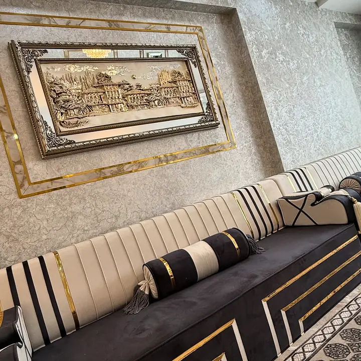 Ivory channel-stitched backrests with black stripes over a black seat with gold fret lines, beneath a large framed relief picture