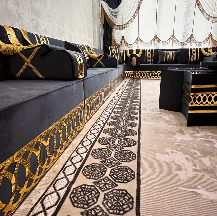 Close view of a black armrest with gold X straps and fringe above the band of interlocking gold ovals on the seat base