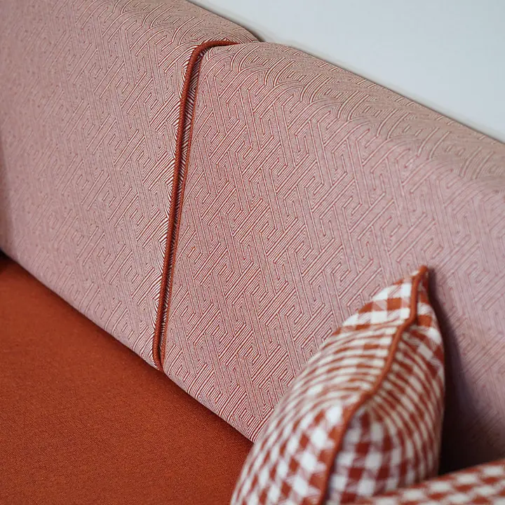 Close-up of blush linen backrests and gingham-check pillows resting on a terracotta linen seat cushion