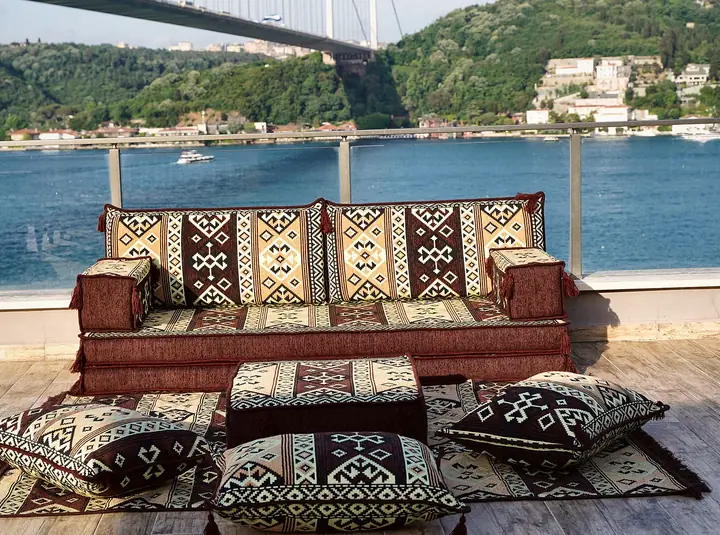 Brown and cream kilim-patterned floor seating with a matching ottoman, loose floor pillows and a coordinated patterned rug