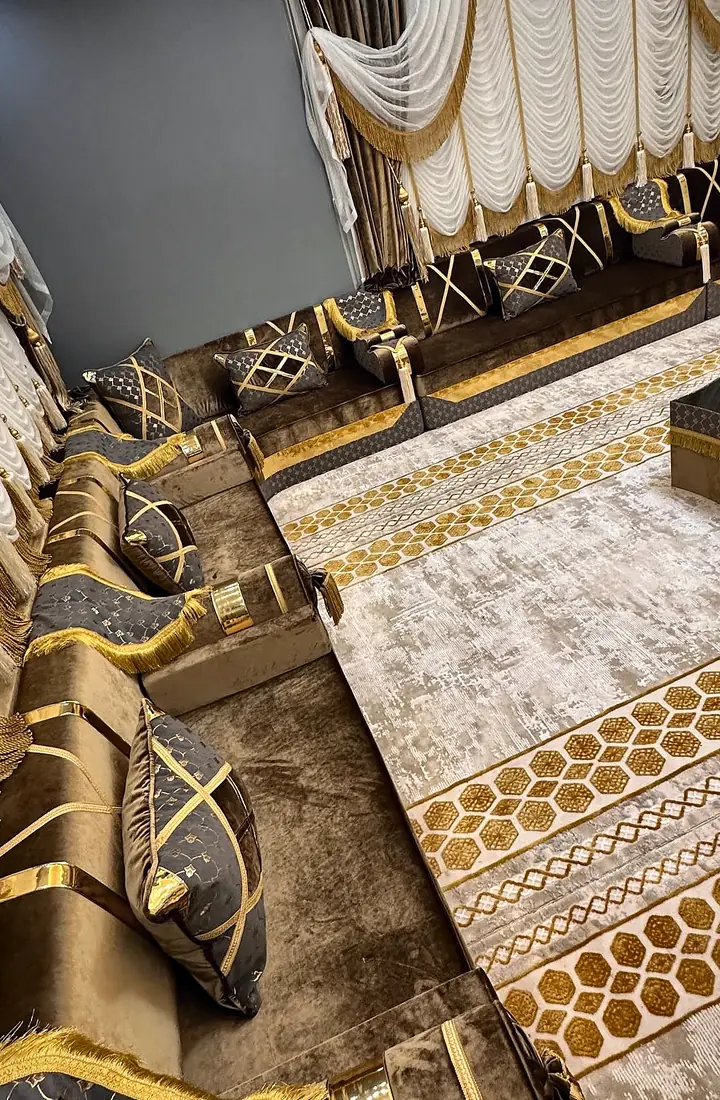 Brown velvet seating running under white festoon curtains, with gold-fringed armrests and a gold honeycomb border on a cream rug