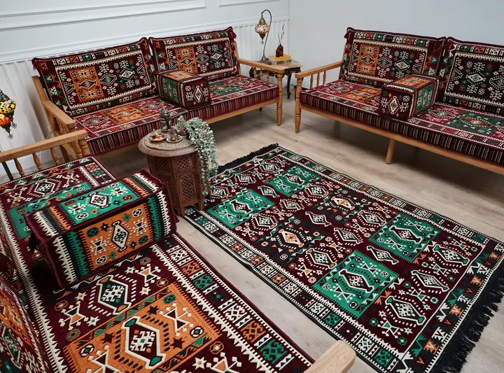 Burgundy, orange and green kilim cushions on pine benches beside a matching fringed rug, seen from behind one bench arm