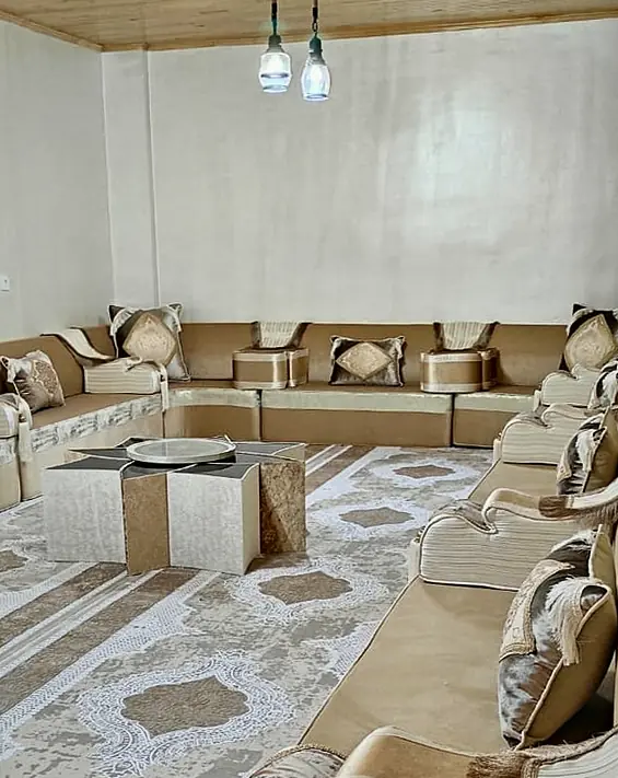 Champagne velvet floor majlis along three walls, with striped armrests, a star-shaped center table and a lace-medallion rug