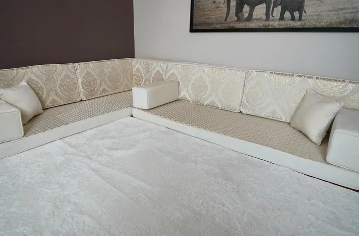 Ivory damask floor seating along two walls on a white rug, placed below a framed elephant print