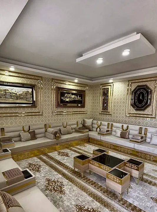 Cream majlis along a wall beneath framed artwork, with small gold cube tables placed between the seating groups