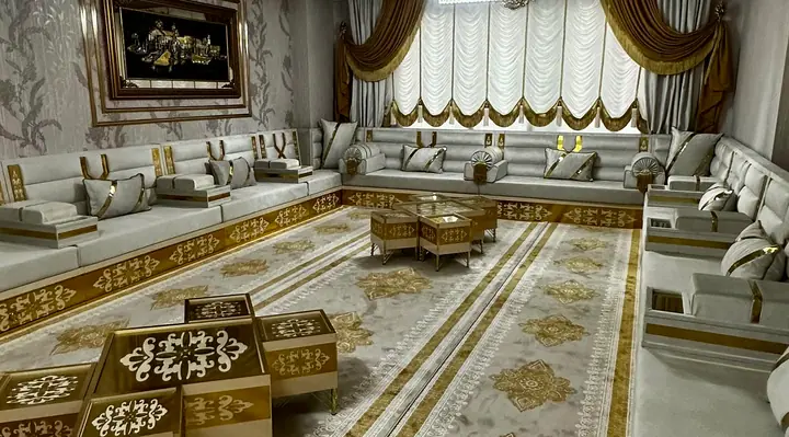 Cream and light gray majlis on a gold-trimmed base along three walls, with a gilded armrest end and gold cube tables on a long carpet