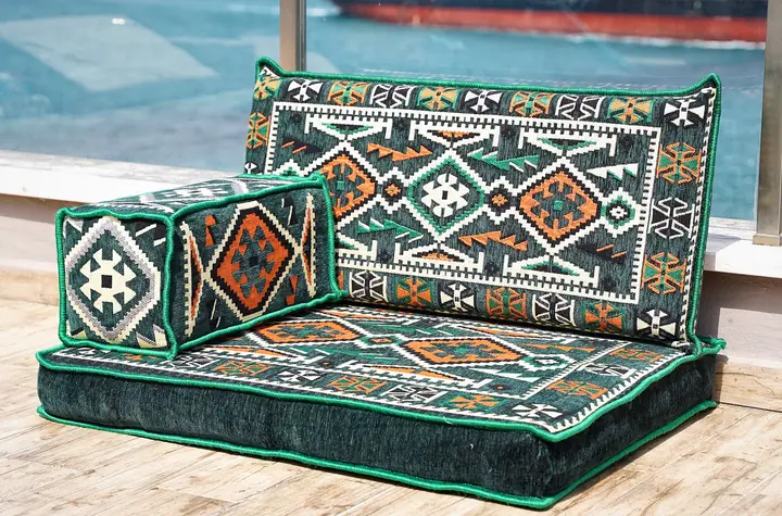 Dark green kilim-pattern single floor seat with one long backrest and a box armrest, set out on an outdoor terrace