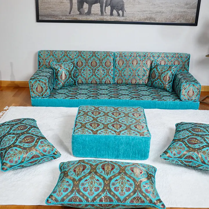 Turquoise diwan floor sofa with tulip-pattern backrests, a fringed ottoman and three floor pillows on a white rug