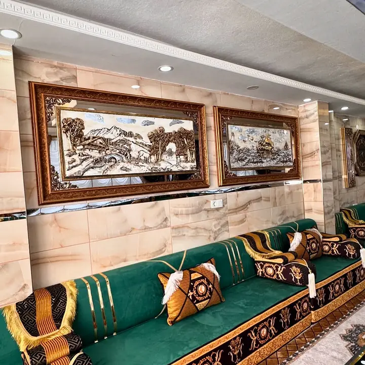 Close view of green velvet backrests with vertical gold stripes, a crest pillow and a striped bolster with a tassel