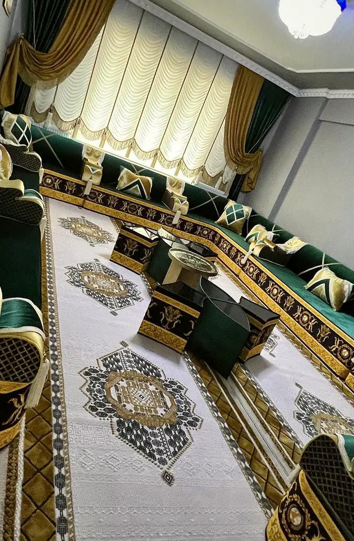 Emerald majlis on a black-and-gold baroque base wrapped around a white rug with black and gold medallions and dark cube tables