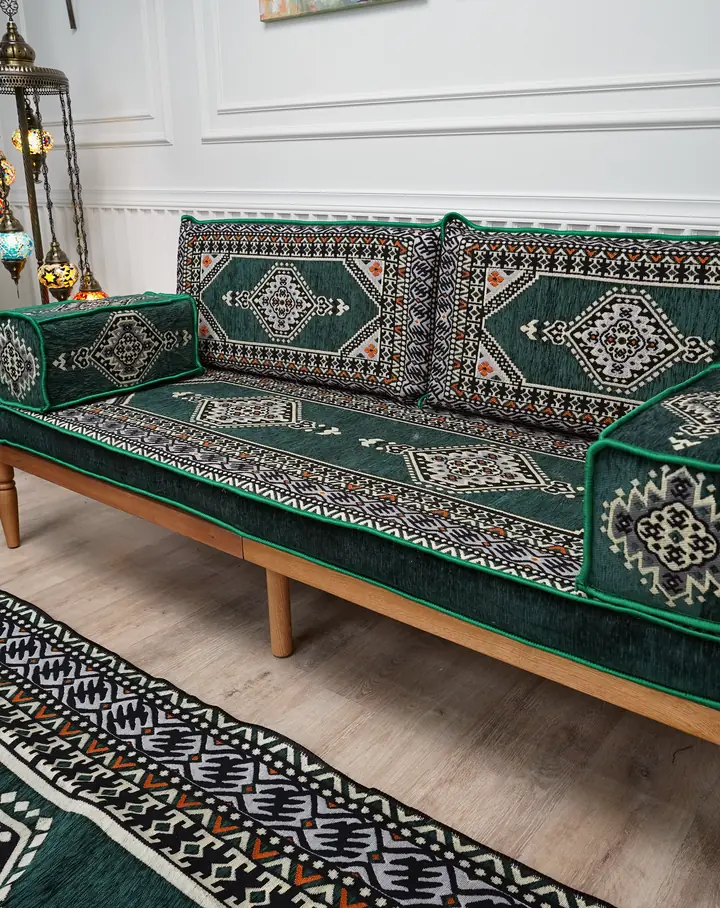 Green kilim-weave cushions on a light wooden bench sofa beside a mosaic floor lamp, with a matching green kilim rug in front