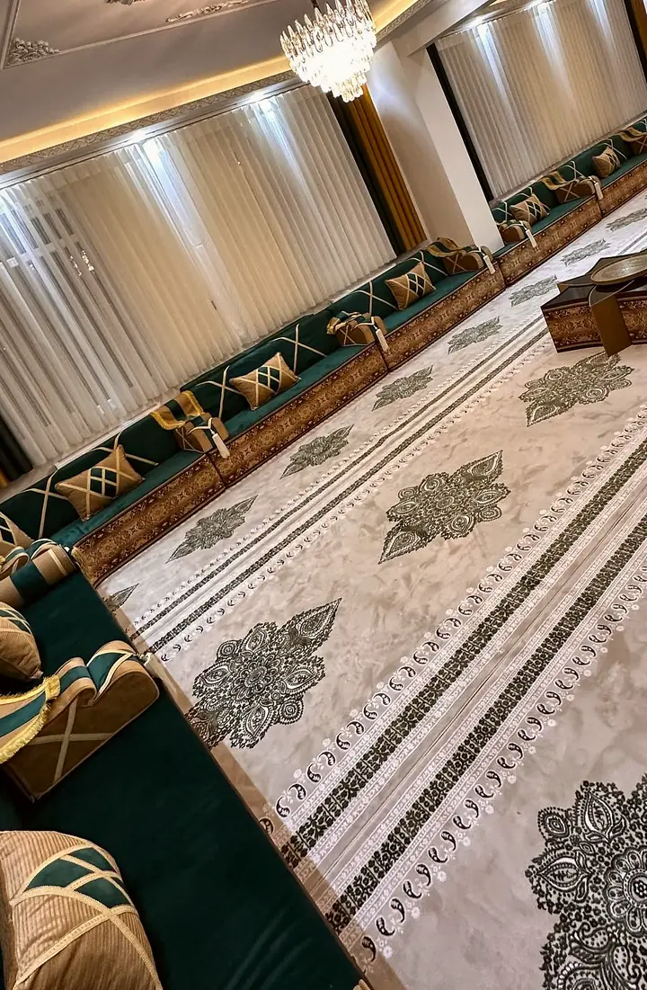 Green velvet seating running the length of a hall under sheer curtains, with caramel bands crossing the pillows