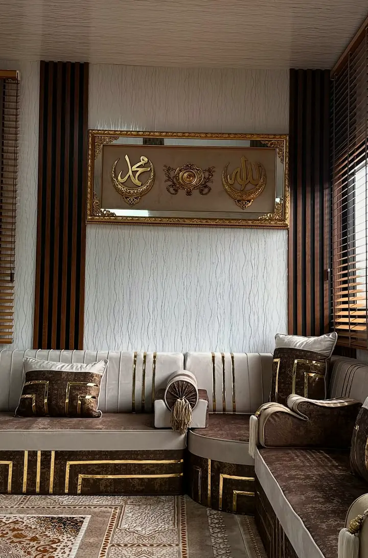 Corner of a two-tone majlis with greige channel-stitched backrests, triple gold bands and brown pillows with gold key motifs