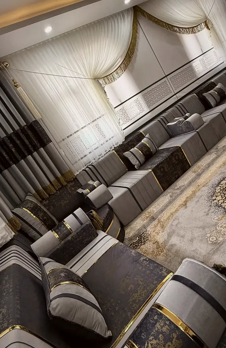 A tilted view follows grey floor seats with dark panels beneath white curtains, with round tables at the edge of the rug.