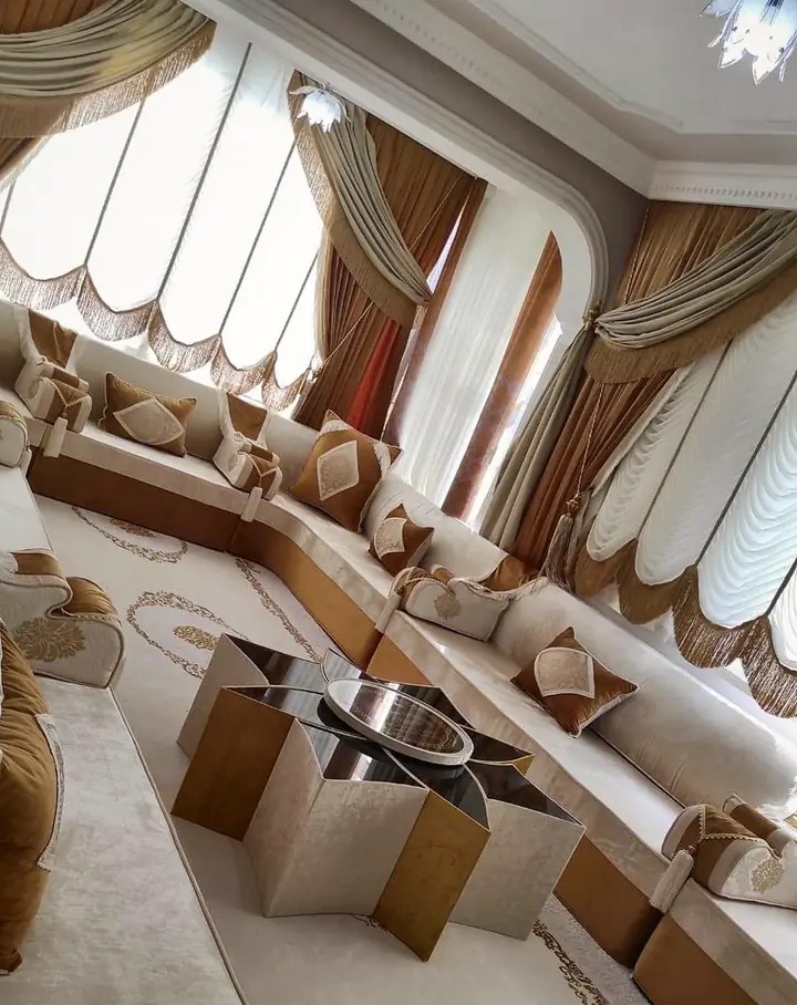Ivory majlis with caramel bands along the walls, a star-shaped table on a cream rug, and caramel curtains with gold-fringed valances