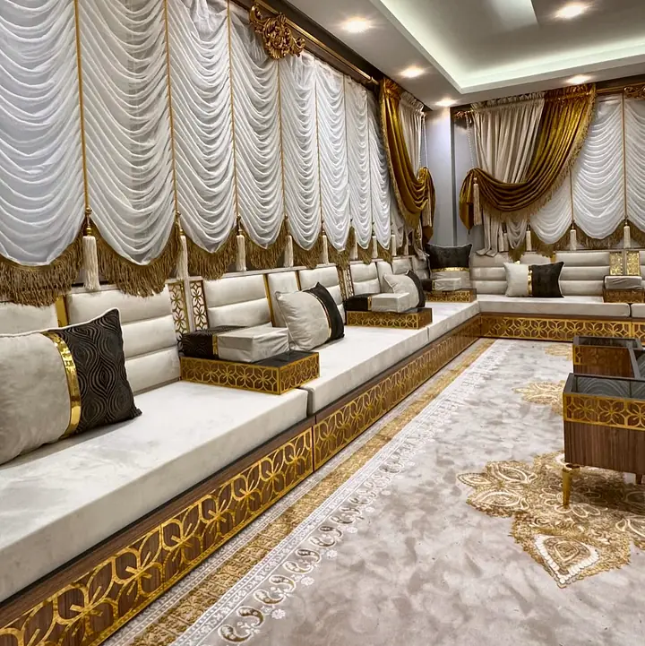 Angled view of ivory seats with a black patterned pillow, gold trim and the walnut base faced with a gold star lattice