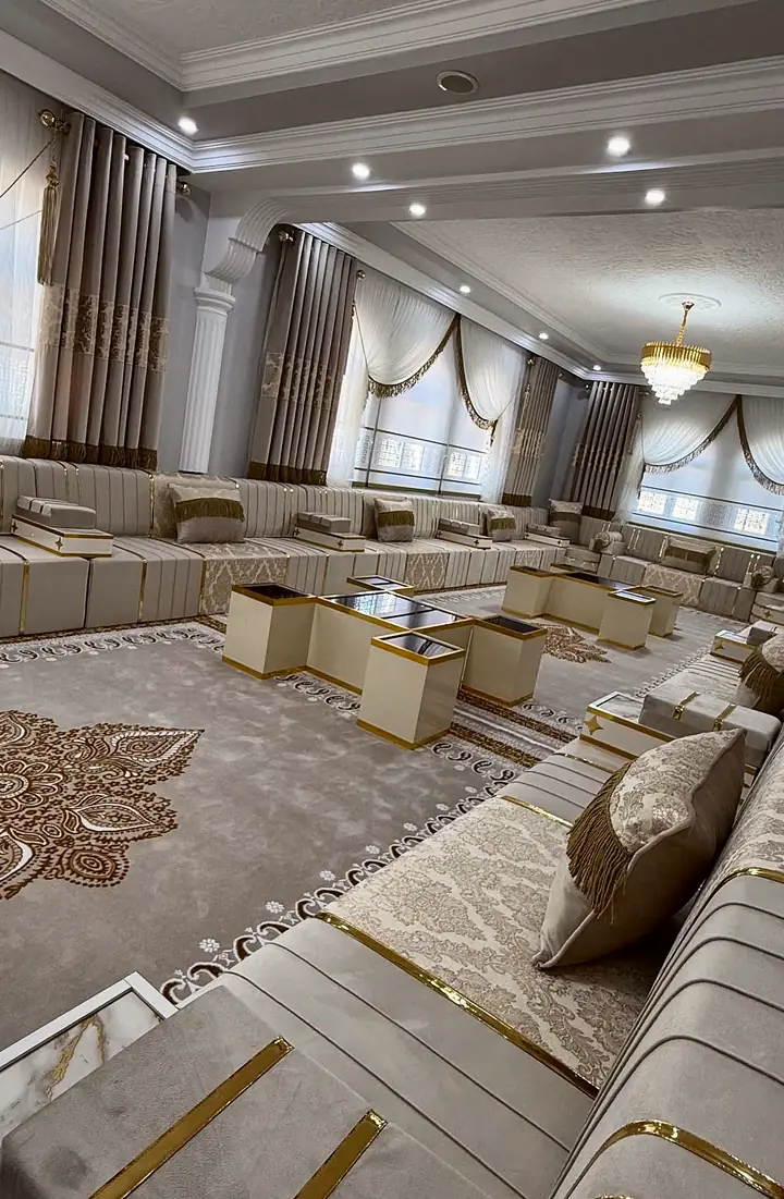 Angled view of ivory channel-stitched seat bases with polished gold strips, damask cushions and box armrests with marble-look tops
