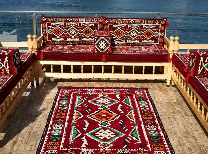 Red geometric kilim cushions on wooden bench seating gathered around a matching red flat-woven rug