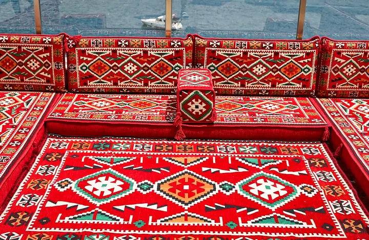 High view of a red kilim U-shaped floor sofa set around its matching rug, showing all three runs of seating