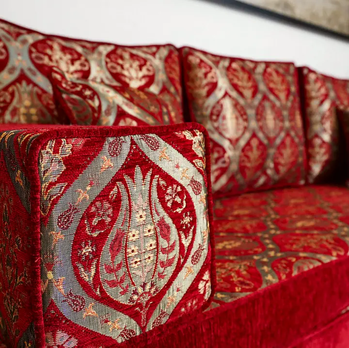 Angled close view of a red tulip-pattern armrest bolster resting against matching back cushions on a floor seat