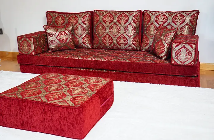 Single red and gold tulip-pattern floor sofa with a square red ottoman resting on a plain white rug in front