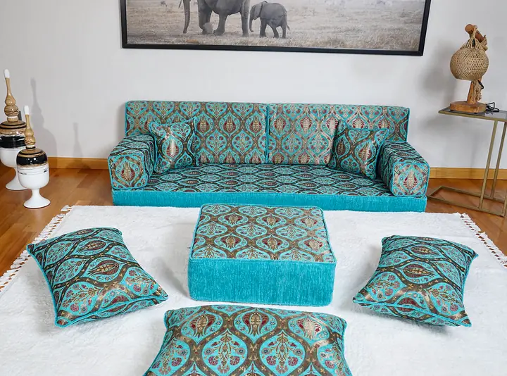 Turquoise ogee-pattern single floor sofa with an ottoman and floor pillows in a bright living room