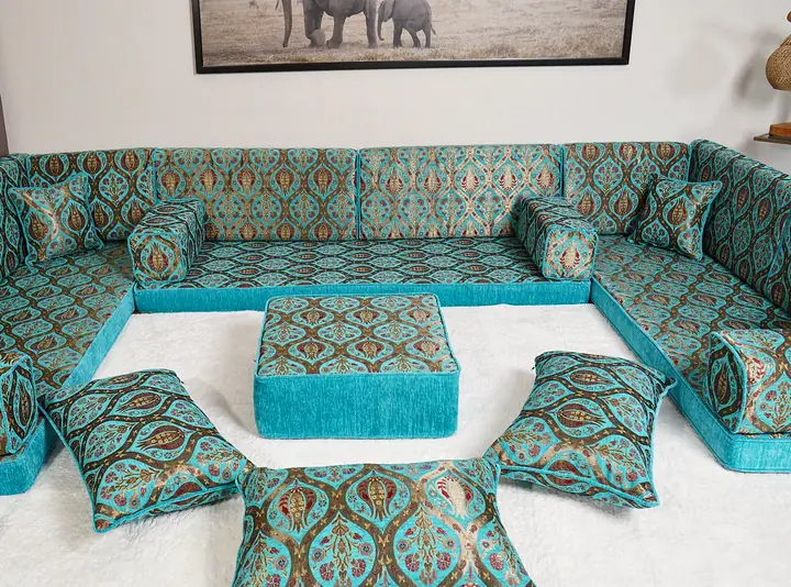 Turquoise tulip diwan on three walls, with an ottoman and floor pillows grouped on a white rug in the middle