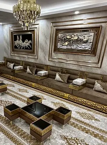 Beige majlis room with gold and black cube side tables between the seats and framed artwork on the wall over them