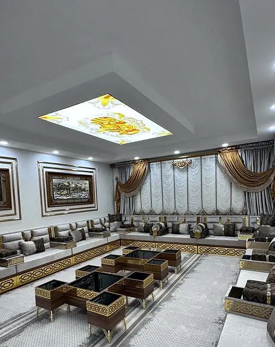 Cream majlis seating set below a rectangular lightbox ceiling panel, with gold and brown accents along the cushions