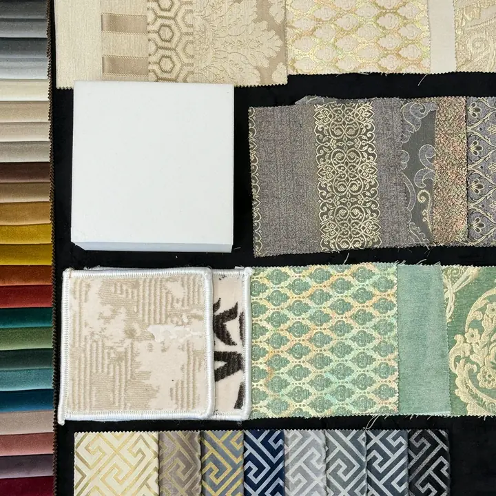 Majlis fabric swatches laid on black velvet: a velvet color strip, cream and mint damasks, Greek-key weaves, a foam block and rug squares