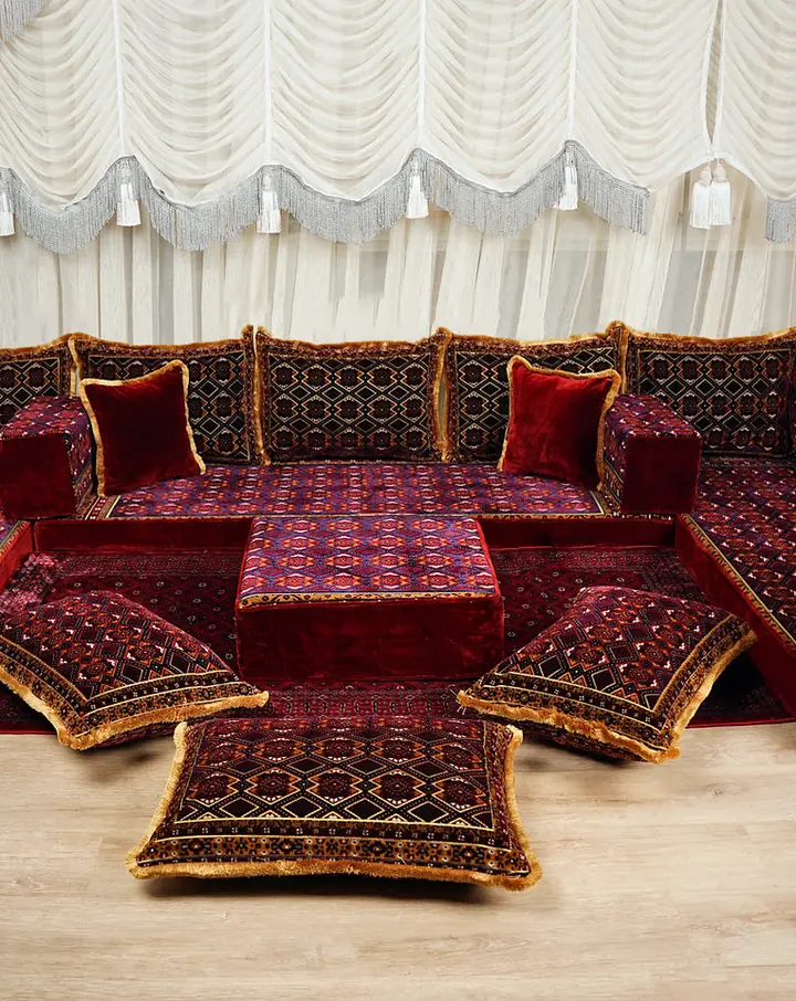 Maroon velvet U-shaped floor sofa set with gold-fringed jacquard cushions, a central ottoman and floor pillows
