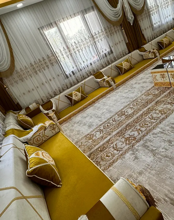 Mustard velvet seats on ivory bases with gold piping along a window wall, with sheer curtains, gold drapes and a pale patterned rug