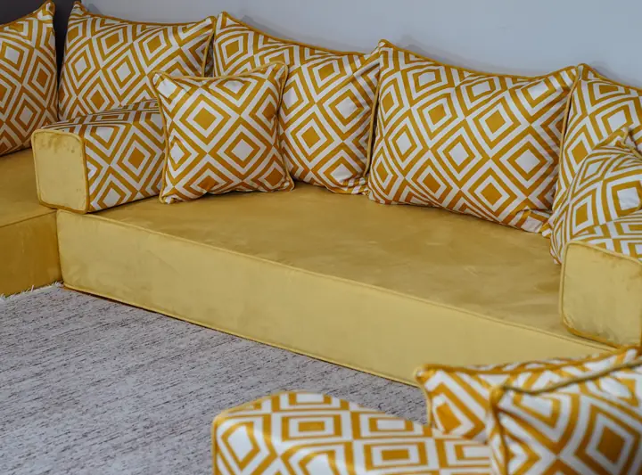 Mustard velvet floor sofa with yellow and white diamond-print backrests, square throw pillows and box armrests against a white wall