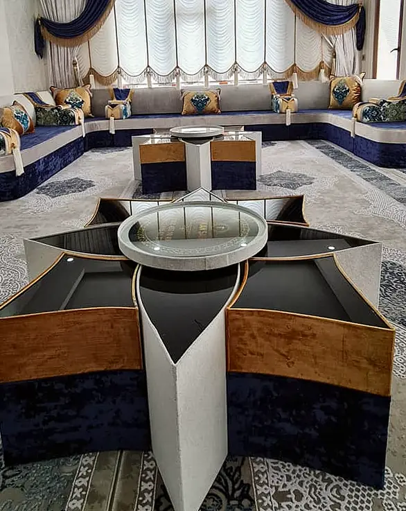Navy and cream majlis along the walls of a long room, with a star-shaped table, festoon blinds with gold fringe and a patterned carpet