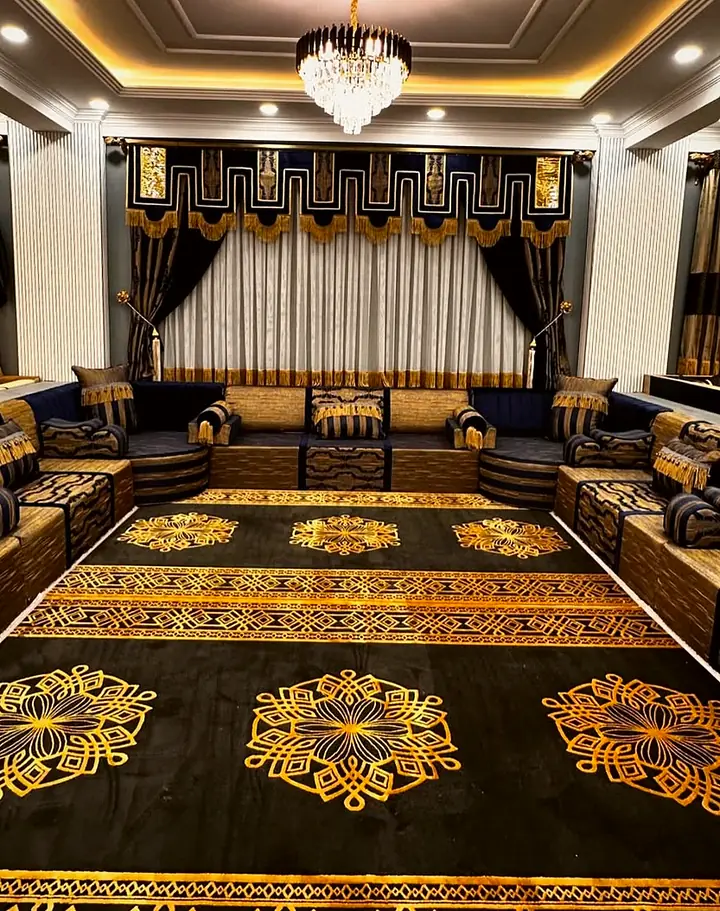 Symmetrical navy and gold U-shaped majlis under a chandelier, with a black rug patterned in gold medallions