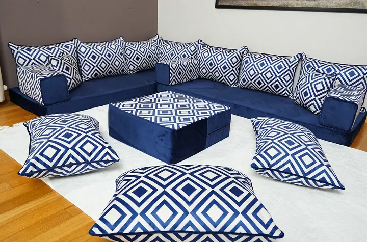 Navy floor cushions form an L around a matching ottoman, with white lattice back pillows and a fringed ivory rug